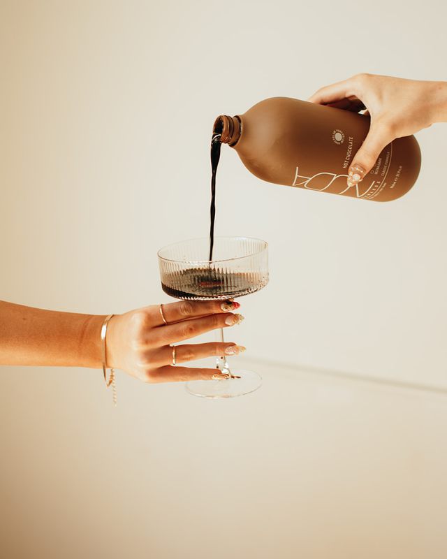 Hand with nail art holding a coupe glass