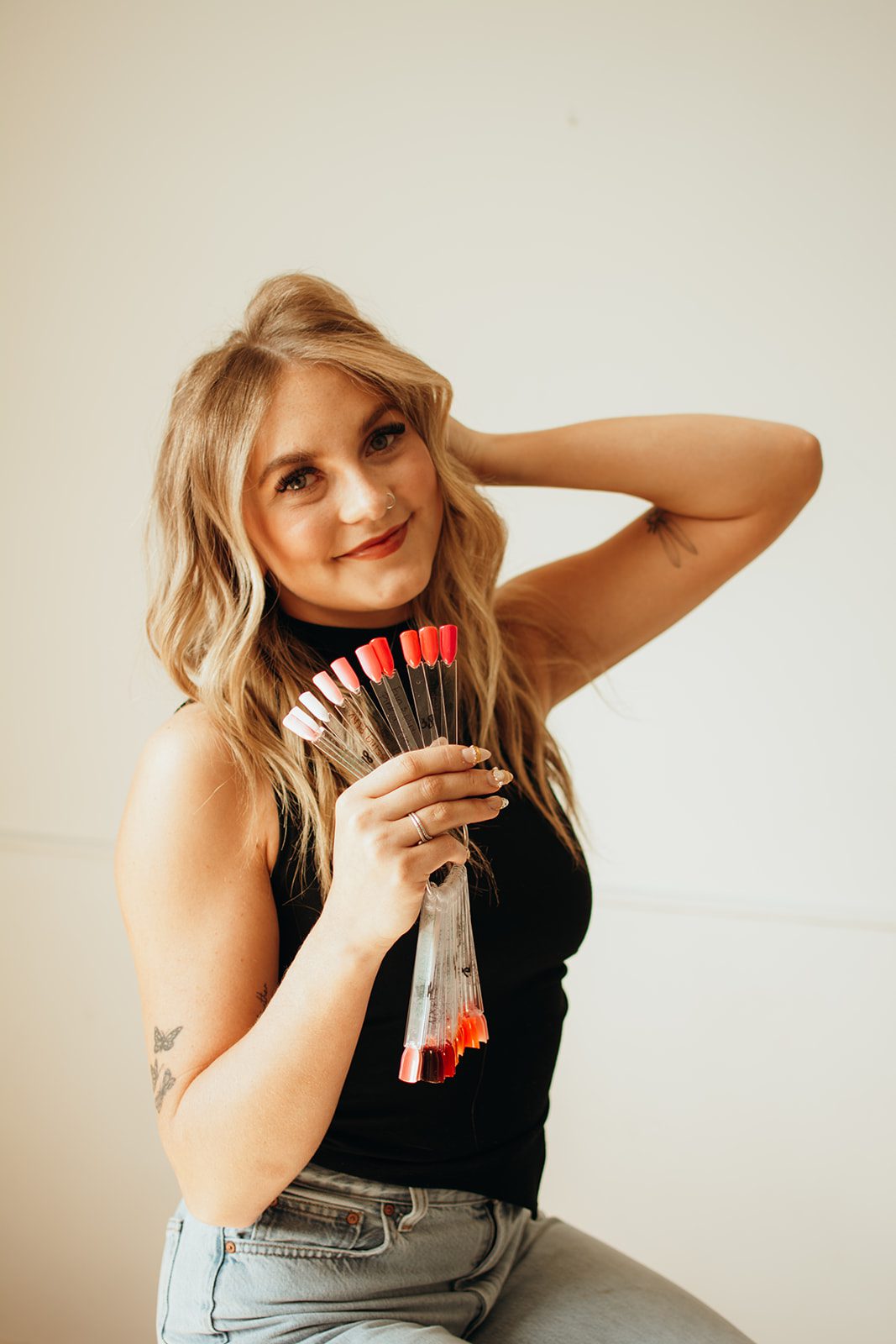Karlee smiling and holding a fan of gel polish colour swatches