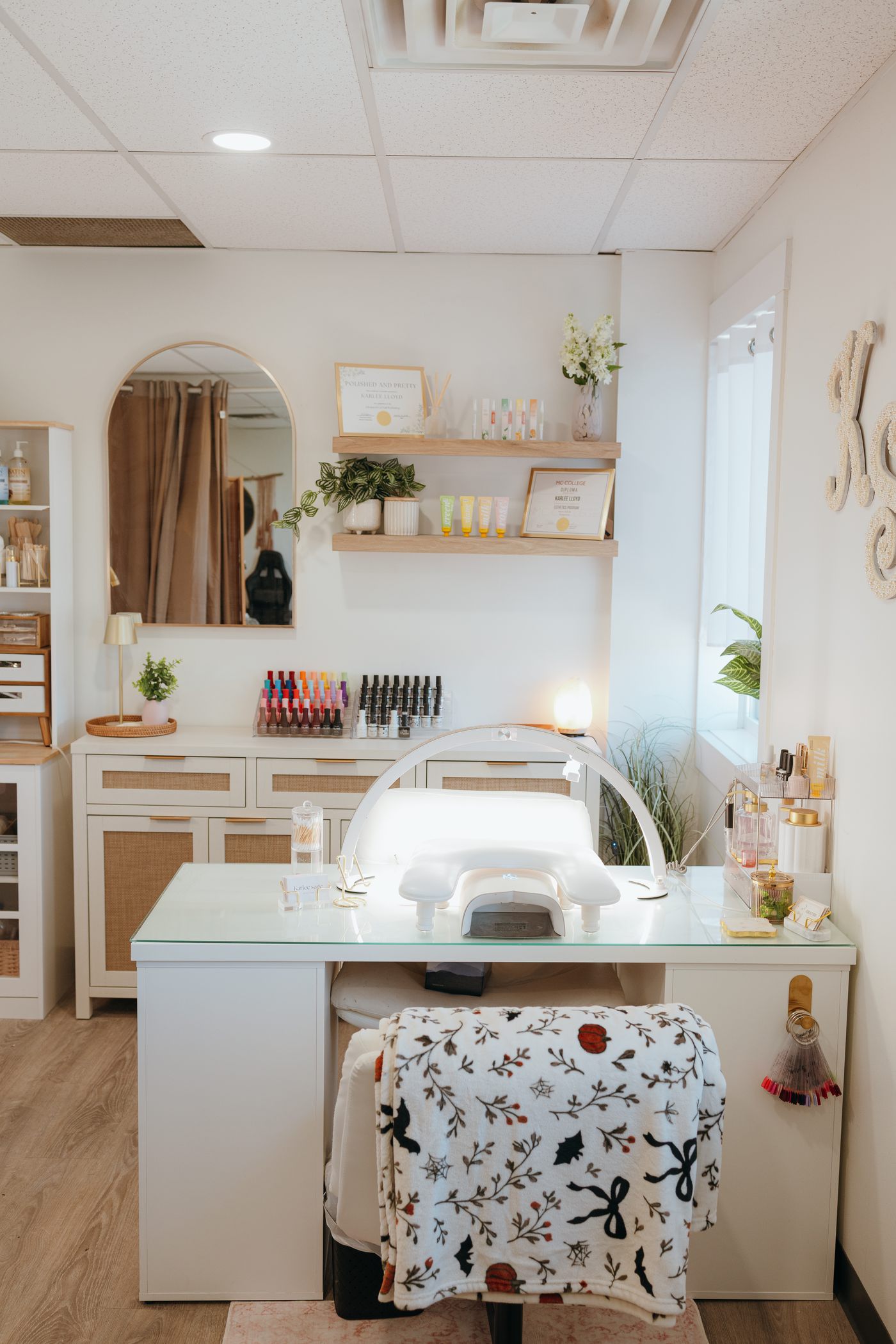 Karlee's nail station with a UV lamp, polish shelves and an arched mirror